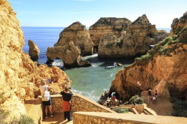 Lagos, Algarve, Portugal- 20 Ekim 2022: Portekiz 'in Algarve kentindeki Ponta da Piedade' nin doğal özelliklerini, kayalıklarını ve kireçtaşı oluşumlarını ziyaret eden insanlar