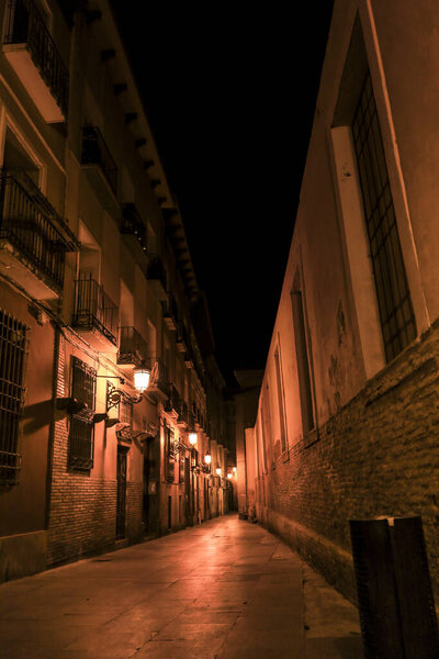 Illuminated streets and Facades of historic houses at night in the old town of Saragossa , Spain