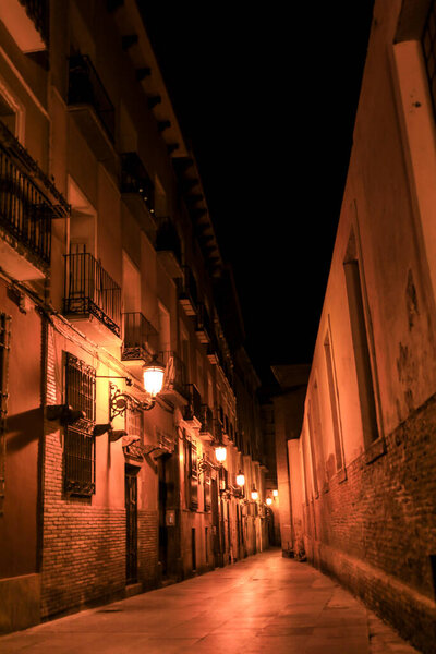 Illuminated streets and Facades of historic houses at night in the old town of Saragossa , Spain