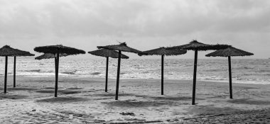 Santa Pola, Alicante, İspanya 'da güneş doğarken kıyıda saman şemsiyeler.