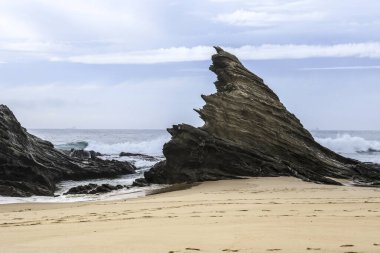 Porto Covo, Alentejo, Portekiz 'de fırtınalı ve rüzgarlı bir günde Samoqueira plajı.