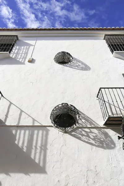 Round windows with wrought iron lattice on whitewashed facade in Ronda, Malaga, Spain
