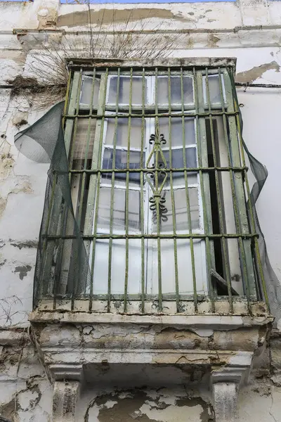 Damaged andalusian house window with wrought iron grill in Rota city