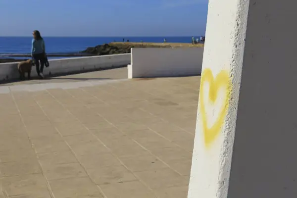 Yellow heart drawn on wall on Playa de la Costilla beach and promenade in Rota city, Cadiz, on a sunny day