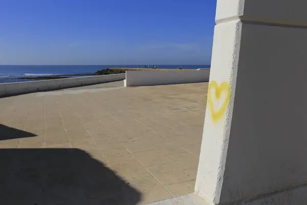 Yellow heart drawn on wall on Playa de la Costilla beach and promenade in Rota city, Cadiz, on a sunny day
