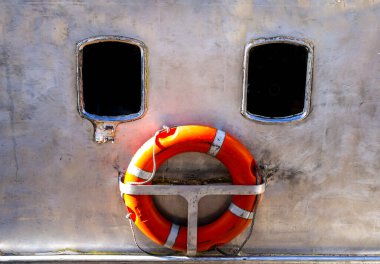 Window and orange lifebuoy of boat forming a conceptual image of a sad face clipart