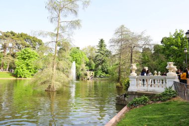 Madrid, İspanya - 8 Nisan 2024: Güneşli bir bahar gününde El Retiro Park 'ın güzel bahçelerinde dinlenen insanlar