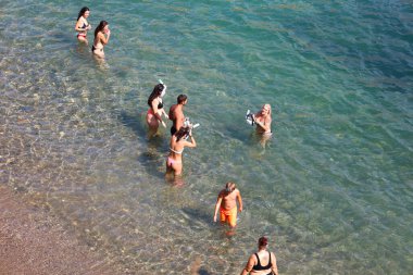 Cabo de Palos, Cartagena, Murcia, İspanya - 10 Ağustos 2024: Güneşli bir yaz gününde Cabo de Palos 'ta Cala Fria Sahili' nde yüzen ve güneşlenen insanlar