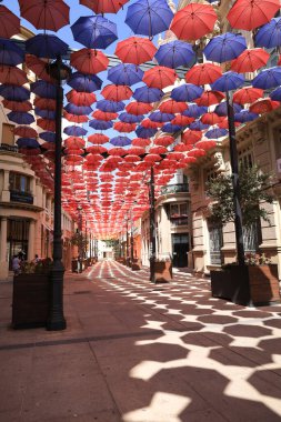 Albacete, Castilla La Mancha, İspanya - 23 Ağustos 2024: Albacete şehrinde Calle Ancha caddesinde mavi gökyüzü altında renkli şemsiyeler