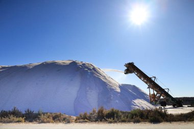 Santa Pola, Alicante, İspanya - 20 Ekim 2024 Santa Pola, Alicante, İspanya 'nın doğal parkındaki tuz dağına tuz atan hasat aracı.