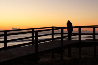 İspanya 'nın güneyindeki Arenales del Sol plajında güneşin doğuşunu seyreden kadın.