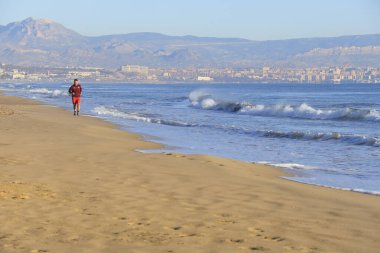 Alicante, İspanya - 24 Kasım 2024: Güney İspanya 'da Arenales del Sol, Alicante sahilinde koşan genç adam