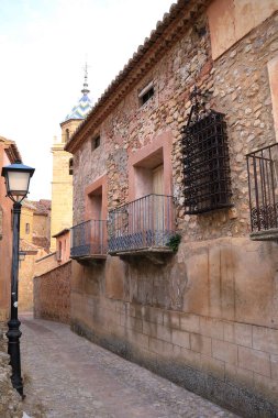 İspanya 'nın Teruel bölgesindeki Albarracin kasabasının arka planında eski cepheleri ve Salvador Katedrali olan dar bir sokak.