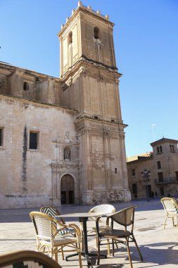 Elche, Alicante, İspanya... 15 Mart 2025 'te, arka planda Santa Maria chuch ve bar terasları olan Ayin Manastırı Meydanı.