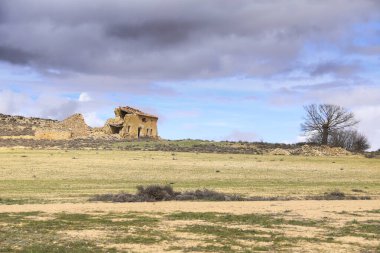 İspanya 'nın Castilla La Mancha bölgesinde ekili araziyle çevrili terk edilmiş taş ev.