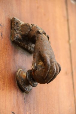 Morella, Castellon, İspanya 'daki eski ahşap kapıya el şeklinde klasik bronz kapı tokmağı.