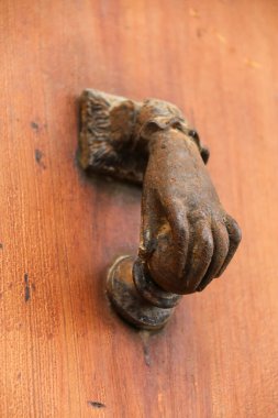 Morella, Castellon, İspanya 'daki eski ahşap kapıya el şeklinde klasik bronz kapı tokmağı.