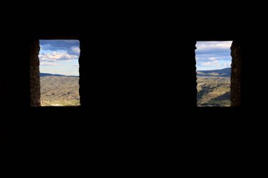 İspanya 'da terk edilmiş bir evin penceresinden görünen bulutlu dağ manzarası