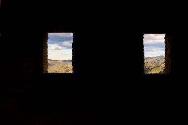 İspanya 'da terk edilmiş bir evin penceresinden görünen bulutlu dağ manzarası