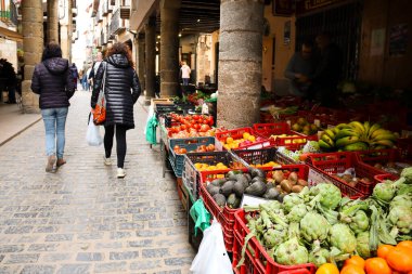 Morella, Castellon, İspanya... 18 Nisan 2025: Blasco de Alagon caddesinde meyva ve sebzelerle dolu market tezgahları ve Morella şehrindeki tarihi eski evler, tepenin üstünde yer alan bir şehir.