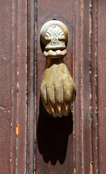 Denia, Alicante, İspanya 'daki eski ahşap kapıya el şeklinde bronz kapı tokmağı.