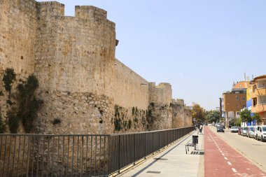 Denia, Alicante, İspanya - 18 Mayıs 2025 Denia Kalesi 'ni çevreleyen duvarlar bir bisiklet yolunun yanında.