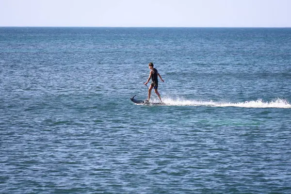 Denia, Alicante, İspanya - 18 Mayıs 2025: İspanya sahillerinde elektrikli ve motorlu sörf tahtası ile sörf yapan genç çocuk