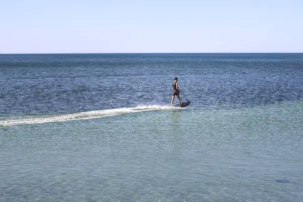 Denia, Alicante, İspanya - 18 Mayıs 2025: İspanya sahillerinde elektrikli ve motorlu sörf tahtası ile sörf yapan genç çocuk