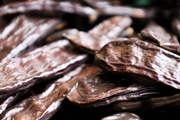 Carob pods background. Fruit of the carob tree, Ceratonia Siliqua