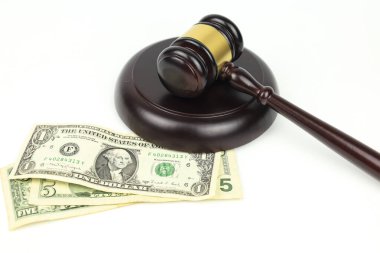 Adalet tokmağı beyaz arka planda dolar banknotlarının yanında. Finans yasalarının sembolü