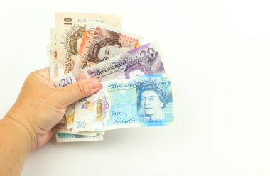 Beyaz arka planda el ele tutuşan sterlin banknotları