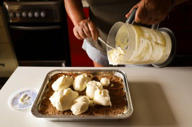 Kadın mutfakta Tiramisu tatlısı yapıyor.