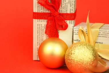 Madrid, İspanya - 8 Ağustos 2025: Kırmızı arka planda Noel tatlıları ve mücevherleriyle eski gazetelere sarılı hediyeler