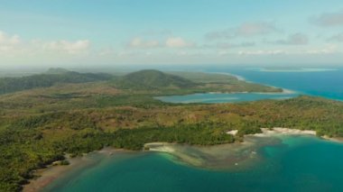Tropikal ada Balabac 'ın kıyı şeridi bulutlu mavi gökyüzüne karşı yeşil ormanla kaplı ve mavi deniz, hava manzaralı. Deniz Burnu: okyanus ve gökyüzü. Palawan, Filipinler