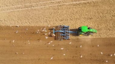 Farming tractor plowing and preparing soil for crops. Spring agronomic activity on agricultural land. Land preparation for farming.