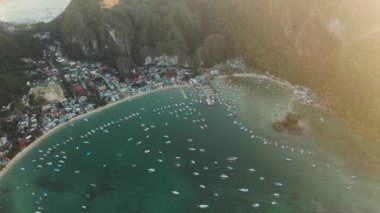 Gün batımında turkuaz gölde bir sürü tekne var. Mavi körfezli deniz burnu ve yukarıdan görünen tekneler. El nido, Palawan, Filipinler. Geleneksel Filipin ahşap outrigger teknesi banca olarak adlandırılır. Yaz ve