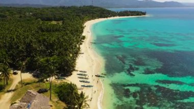 Beautiful sandy beach with palm trees and sea surf with waves. Pagudpud, Ilocos Norte, Philippines.