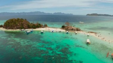 Tropikal adası, kumlu sahili, turkuaz suyu ve mercan resifi olan havadan deniz manzaralı bir koy. Bulog Dos, Filipinler, Palawan. Tropikal adada turist tekneleri.