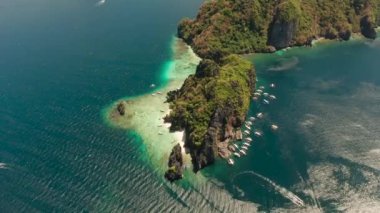 Tropikal adanın üzerinde kumlu sahil ve mercan kayalıkları olan turist teknelerinin insansız hava aracı görüntüsü. El nido, Filipinler, Palawan. Yaz ve seyahat tatil konsepti
