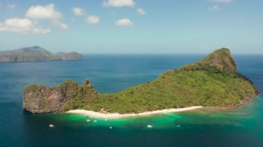 Kumlu plajlı, yeşil yapraklı ve palmiye ağaçlı hava aracı tropikal adası. Gök mavisi ve berrak suyu olan bir göl. El Nido, Palawan Filipinleri 'ndeki helikopter adası. Yaz ve seyahat tatil konsepti