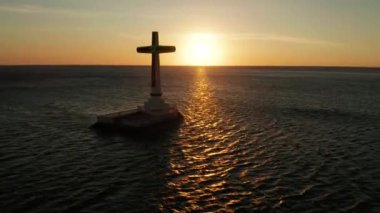 Batık mezarlıkta katolik haçı, gün batımında deniz manzaralı. Batık Mezarlıkta gün batımı Camiguin Adası Filipinleri.