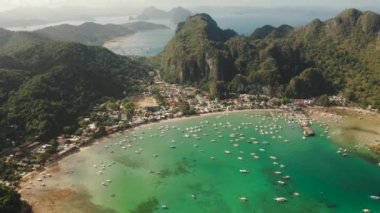 Mavi gölü ve turist tekneleriyle koydaki hava aracı. Palawan adasındaki ünlü turist kasabası El Nido. Mavi körfezli deniz burnu ve yukarıdan görünen tekneler. Yaz ve seyahat tatili