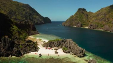 Kumsalı ve kayalıklarla çevrili berrak mavi suyu olan tropik hava aracı peyzajı. El nido, Filipinler, Palawan. Tropikal kayalık adaları, okyanus mavisi suları olan deniz burnu. Yaz ve seyahat
