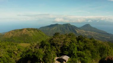Tropikal manzara: Ormanlı dağlar, mavi gökyüzü bulutlu, üst manzara, Camiguin, Filipinler. Tropikal adada dağ zirveleri ormanla kaplı bir dağ manzarası.