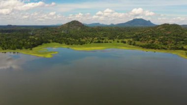 Top view of lake and jungle in the valley against the background of mountains and clouds. Sorabora lake, Sri Lanka.