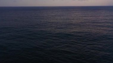 Aerial drone of ocean sunset over the calm water surface.