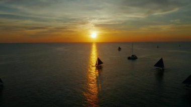 Yelkenli tekneleri, Boracay, Filipinler 'deki hava manzaralı deniz yüzeyinin üstünde renkli bir günbatımı. Su yüzeyine yansıyan güneş. Okyanusun üzerinde gün batımı. Deniz manzarası, yaz ve tatil konsepti