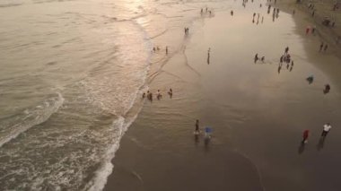 Okyanus kıyısında kumlu parangtritler, büyük dalgalar, gün batımında tropik tatil köylerinde yaşayan insanlar. Yogyakarta, Endonezya. Hava manzaralı deniz manzaralı, okyanus manzaralı ve güzel plajlı. Seyahat konsepti. Endonezya, java