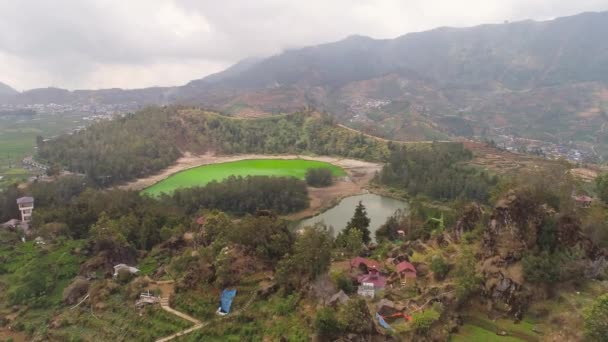インドネシアのディエンプラトーにある火山性硫黄湖テラガ ワルナ 山の間に緑の水と山の熱帯の風景湖 この湖は ウォノソボの主要な観光地の1つです — ストック動画