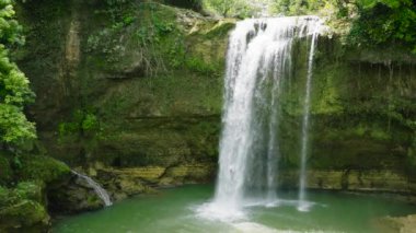 Waterfall in the tropical forest in slow motion. Aerial view of Ben-Ben Falls waterfall in a mountain gorge. Negros, Philippines.